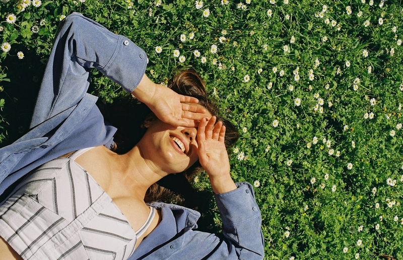 Eine Frau liegt in einer sommerlichen Blumenwiese